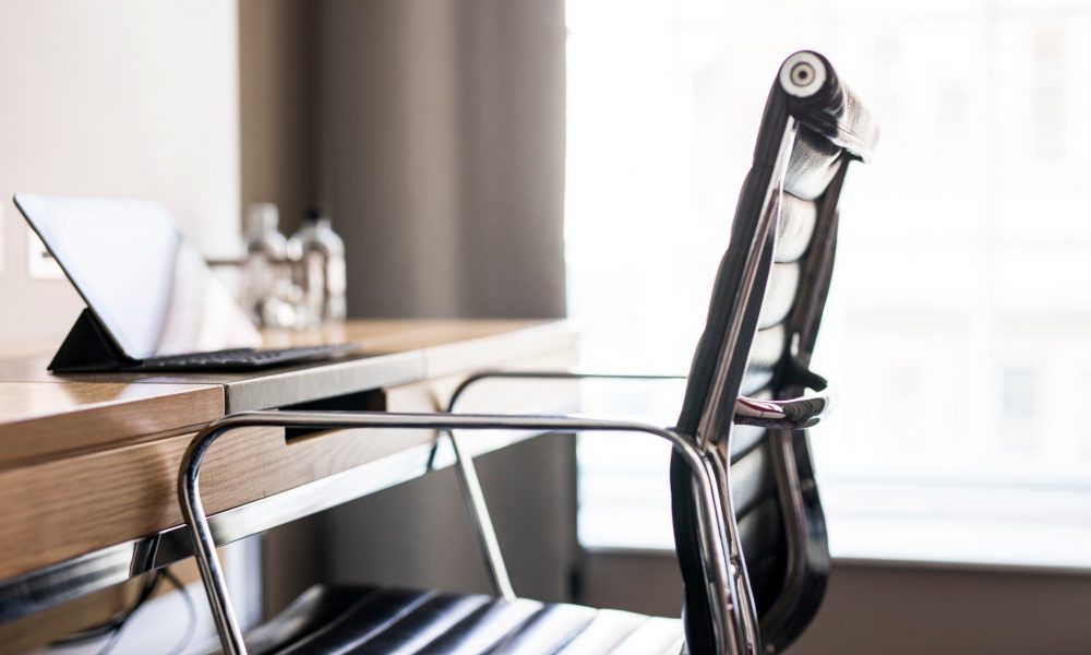 a-work-study-desk-with-black-leather-chair-against-a-bright-natural-light-white-window-computer_t20_NGPmJQ